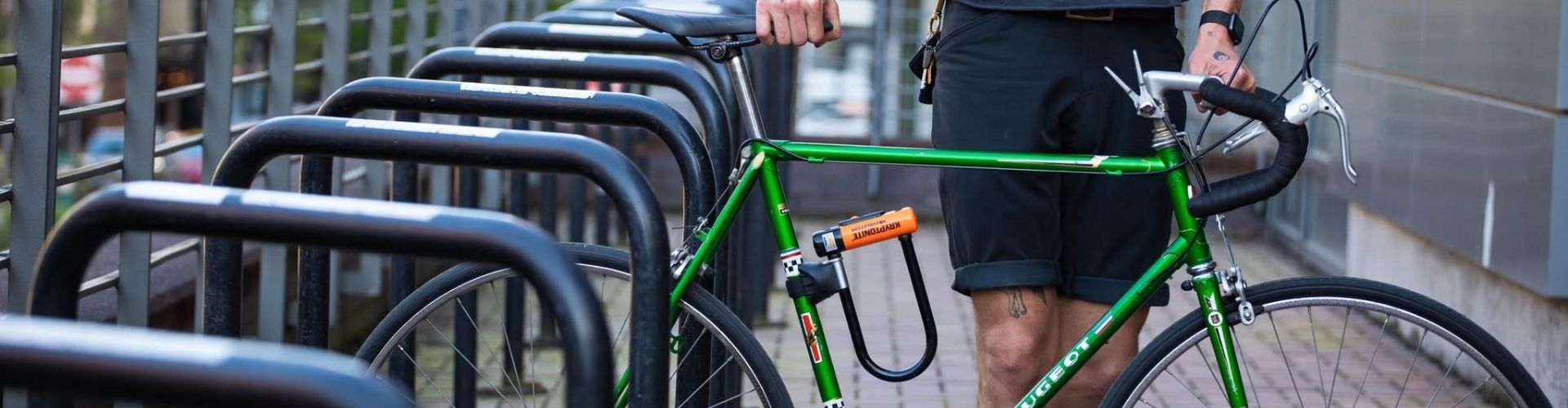 Homme en train de ranger son vélo vert avec antivol
