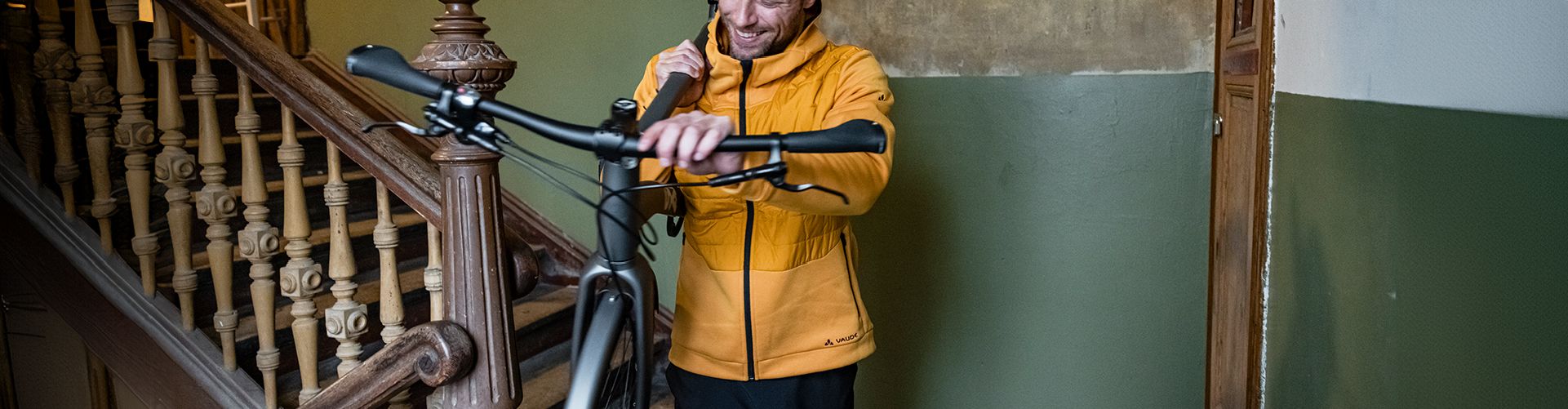 un homme descend son velo dans la cage d'escalier de son immeuble pour partir au travail