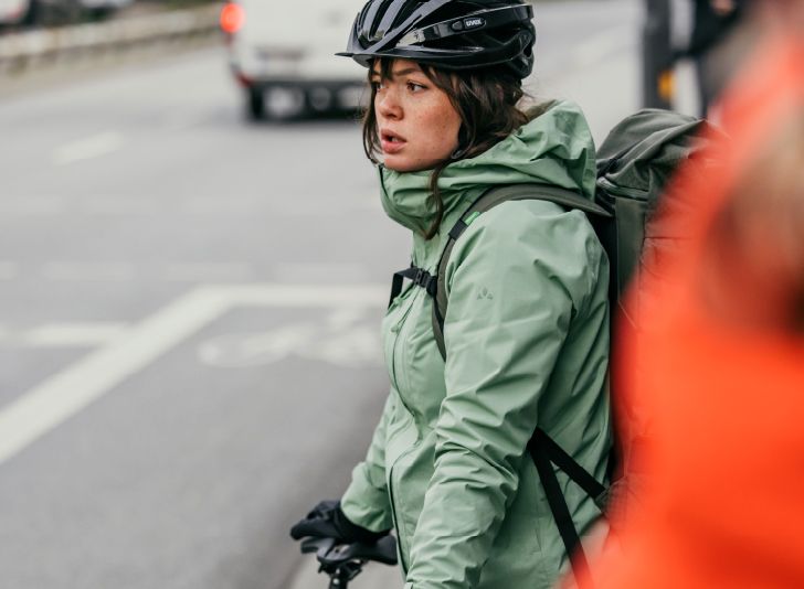 une jeune femme en velotaf avec une veste de pluie